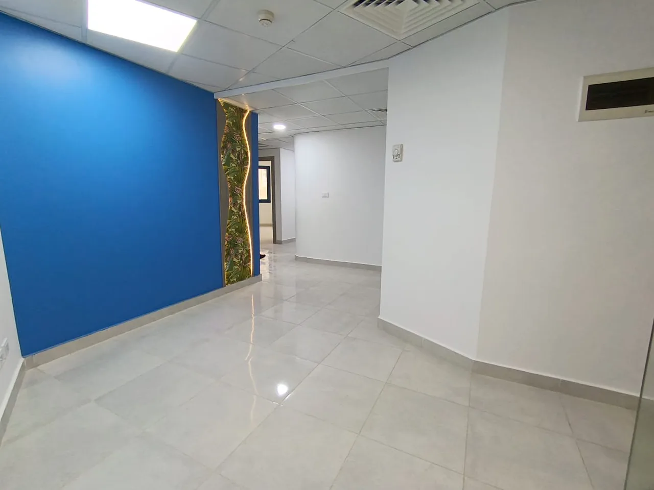 Reception area with a blue feature wall and a lit green panel in a medical clinic on the Maadi Corniche, Cairo