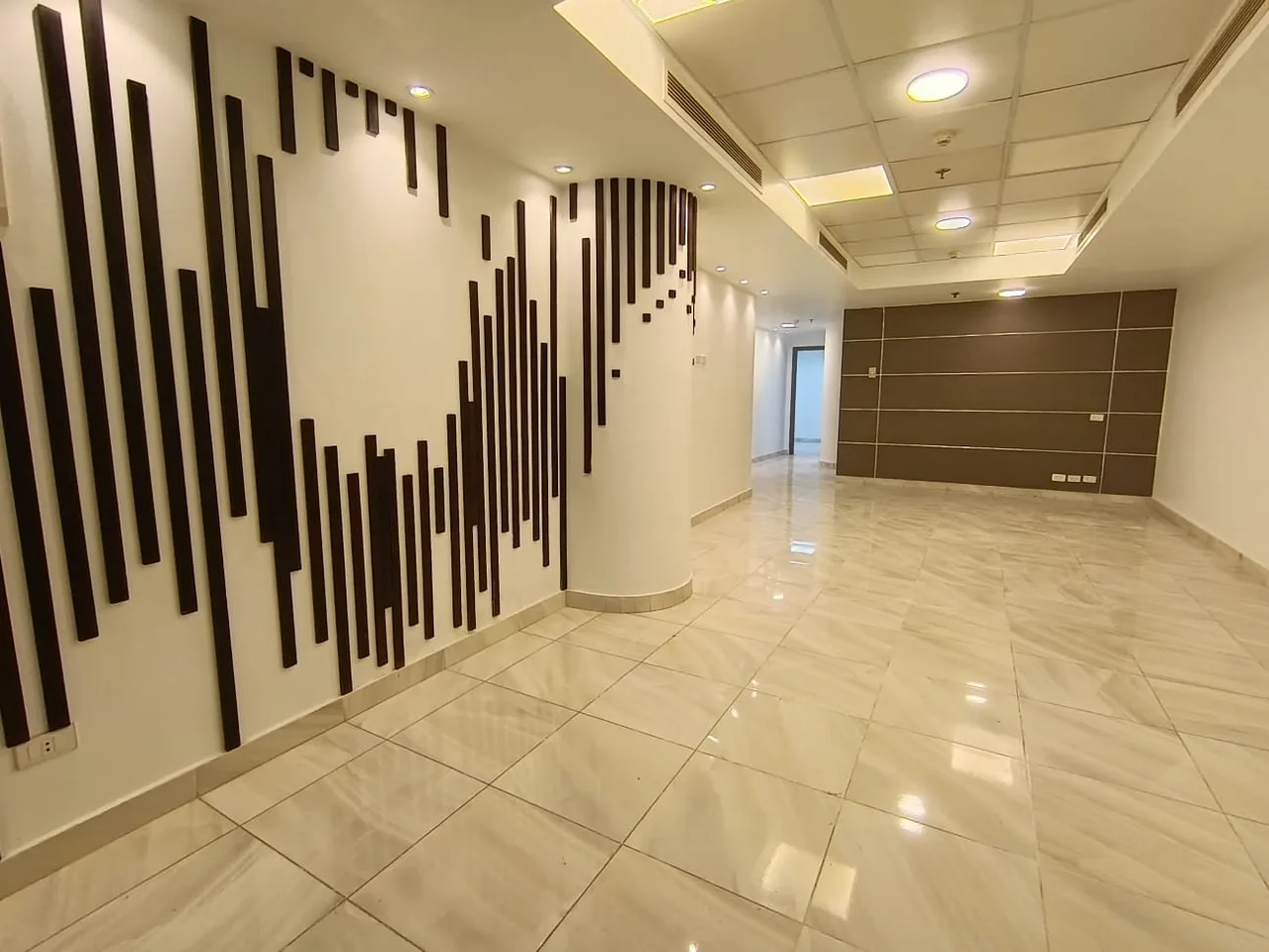Open hall with a dark wooden-slat feature wall and marble-effect tiles in a clinic on the Maadi Corniche, Cairo
