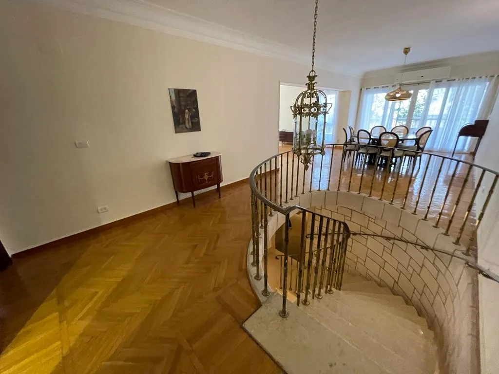 Spiral staircase opening onto the parquet living and dining area of a ground-floor duplex in Degla, Maadi