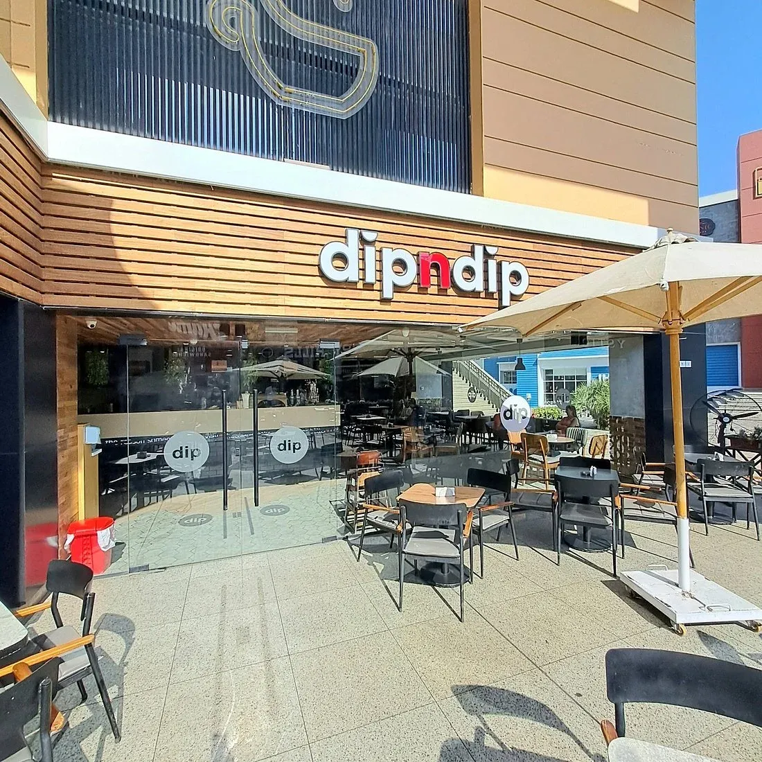 مدخل كافيه الحلويات dipndip بمظلات وطاولات خارجية في كايرو فستيفال سيتي
