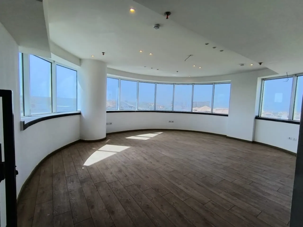 Finished empty office with curved windows and wood-look flooring in a full floor for rent in Fifth Settlement, New Cairo