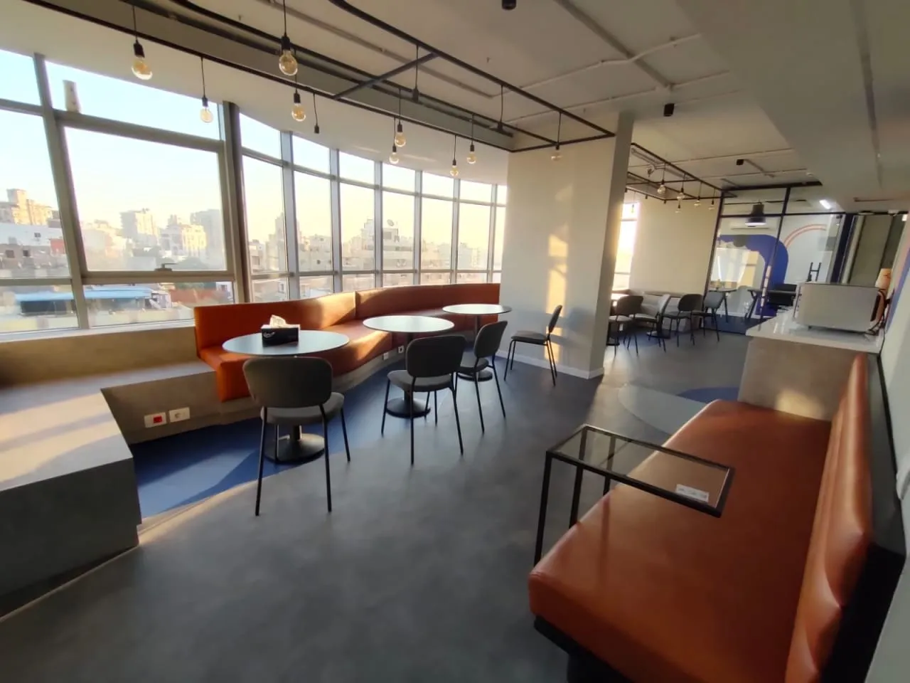Staff lounge with orange booth seating and wide windows over the city in a full floor for rent in New Maadi, Cairo