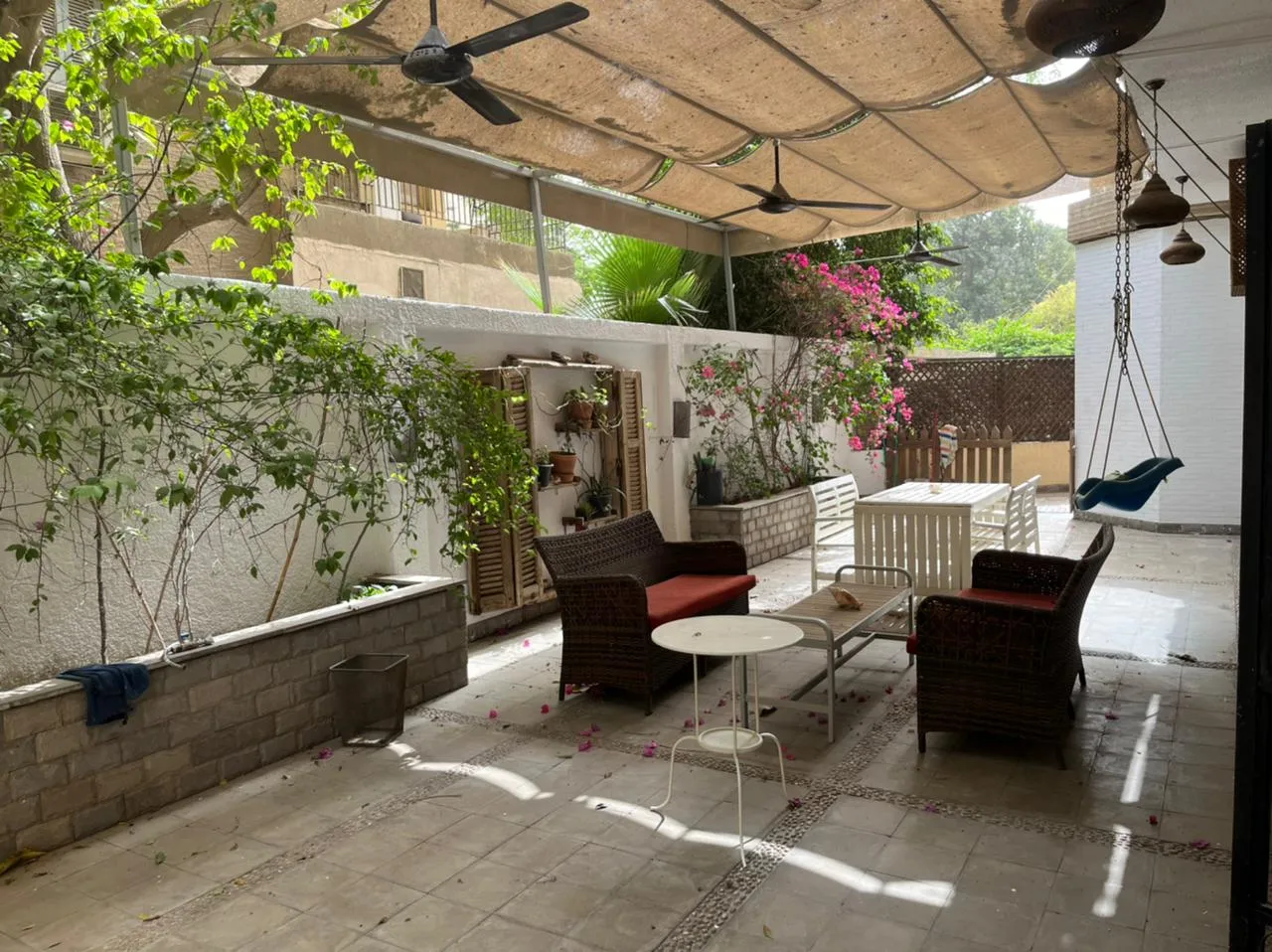 Shaded garden terrace with rattan seating, ceiling fans and climbing plants at a ground floor in Degla, Maadi
