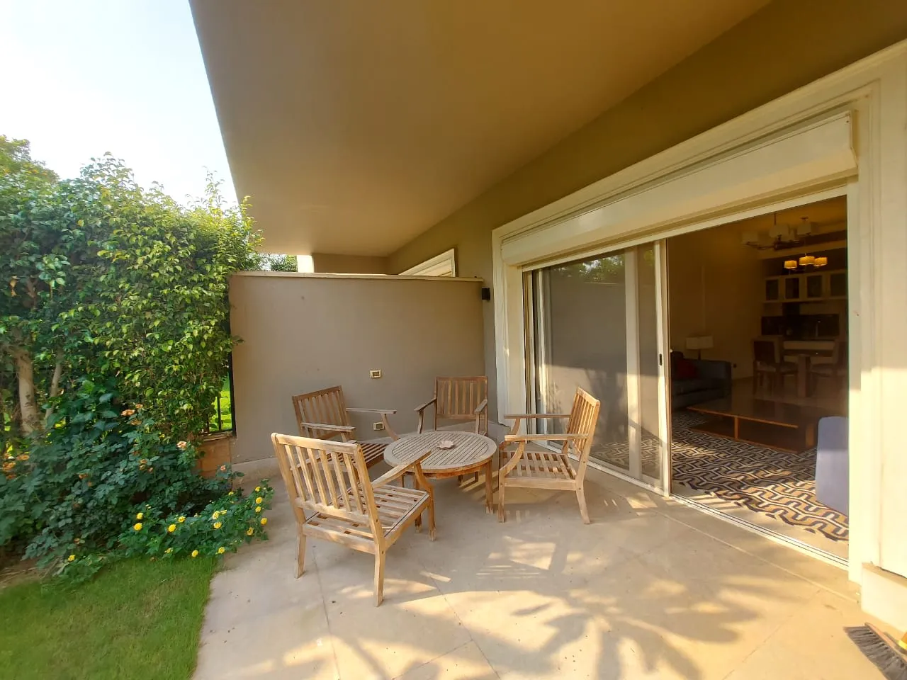 Garden patio with wooden chairs beside a sliding door to the living room of a ground floor in the Fifth Settlement