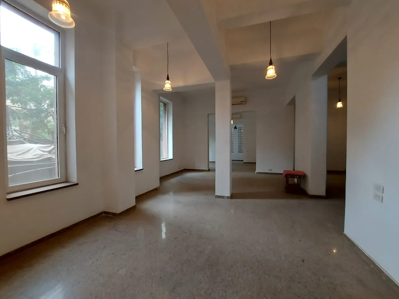 Bright reception with tall windows, pendant lights and square columns in a ground floor apartment in Zamalek