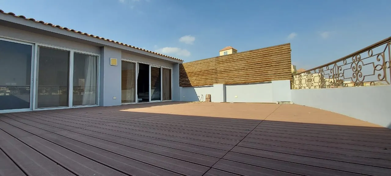 Wooden roof deck with a slatted privacy screen outside a penthouse for sale in New Cairo