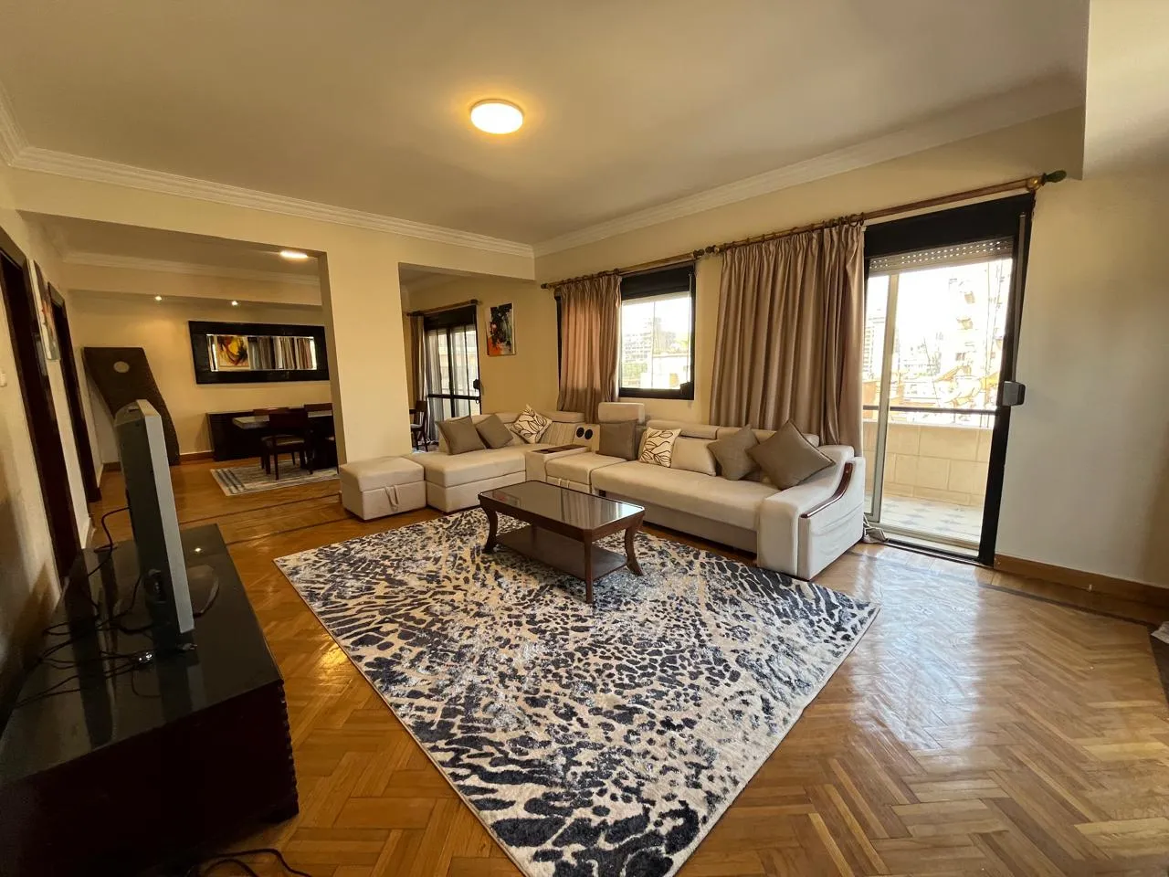 Furnished living room with a corner sofa and herringbone parquet in a penthouse for rent in Zamalek