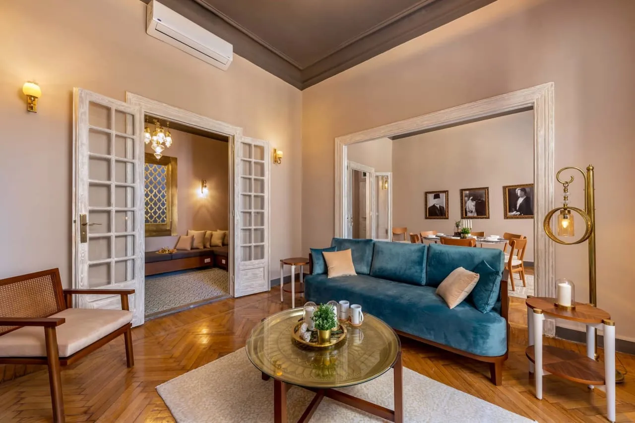Living room with a teal velvet sofa, high ceilings and panelled glass doors in a serviced apartment in Downtown Cairo