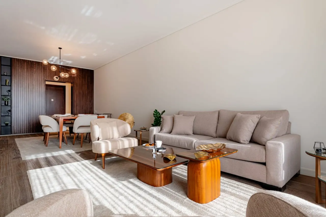 Bright living room with beige sofas, a wooden coffee table and a dining corner in a serviced apartment in New Cairo