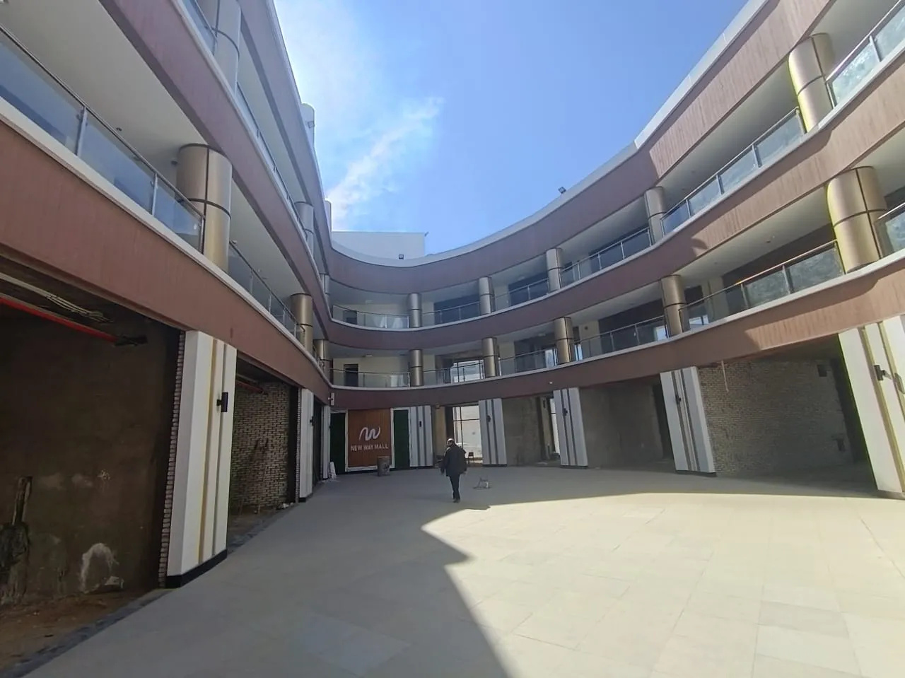 Curved open-air courtyard lined with ground-floor shop units in a commercial building in New Cairo