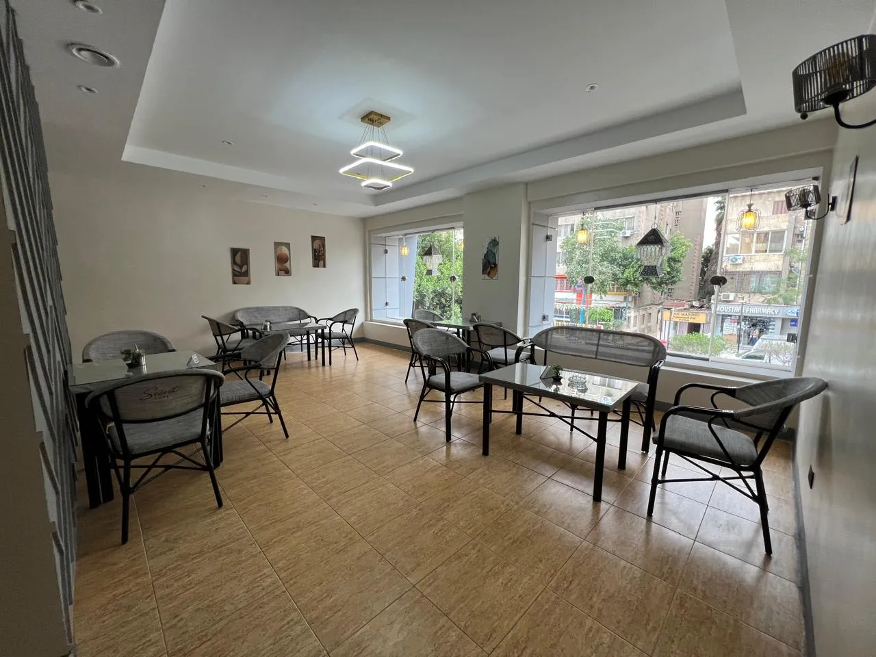 Café tables and wicker chairs beside large street-facing windows in a shop for rent in New Maadi, Cairo