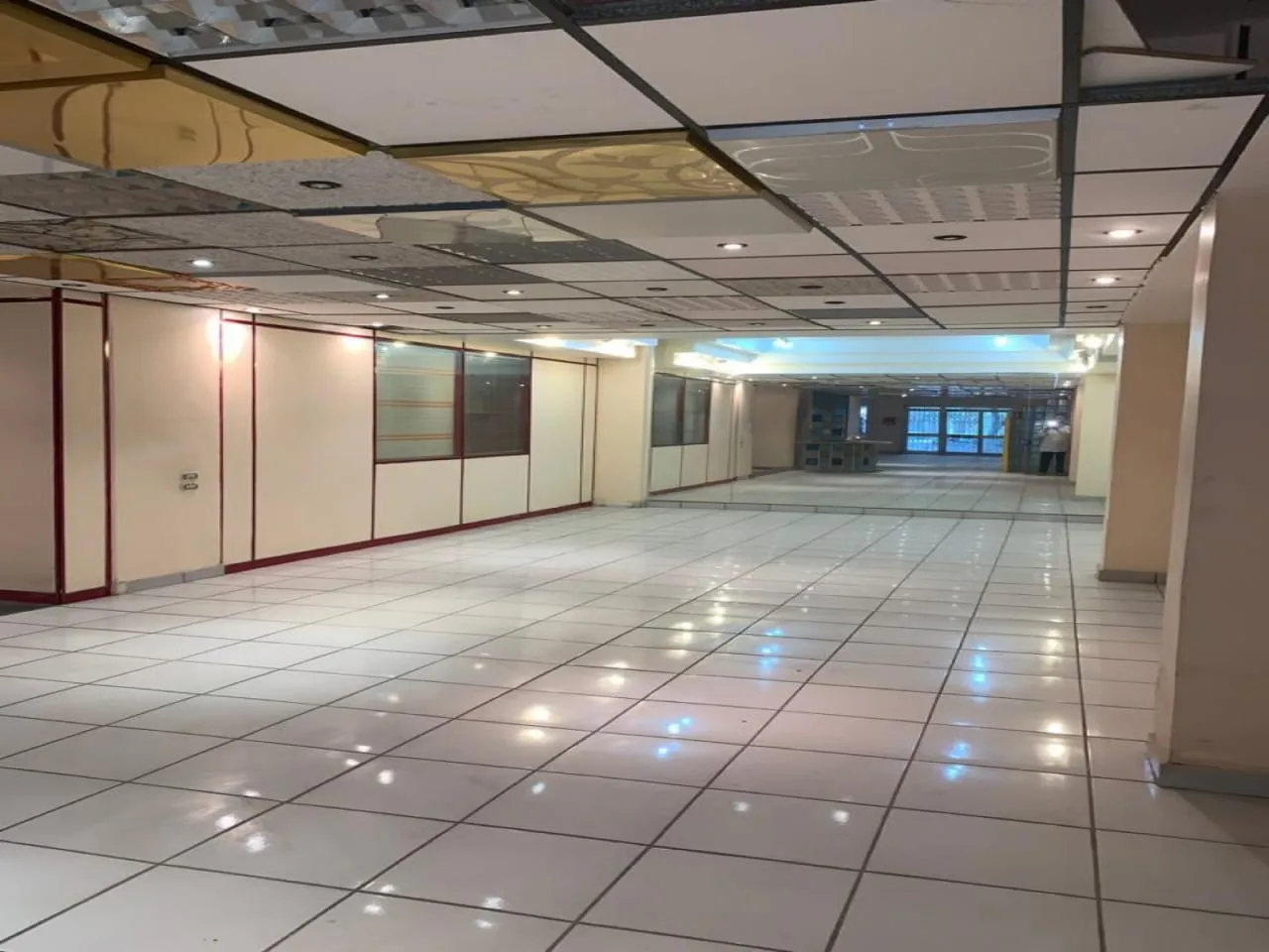 Open sales floor with glossy white tiles and glass partitions in a shop for rent in New Maadi, Cairo