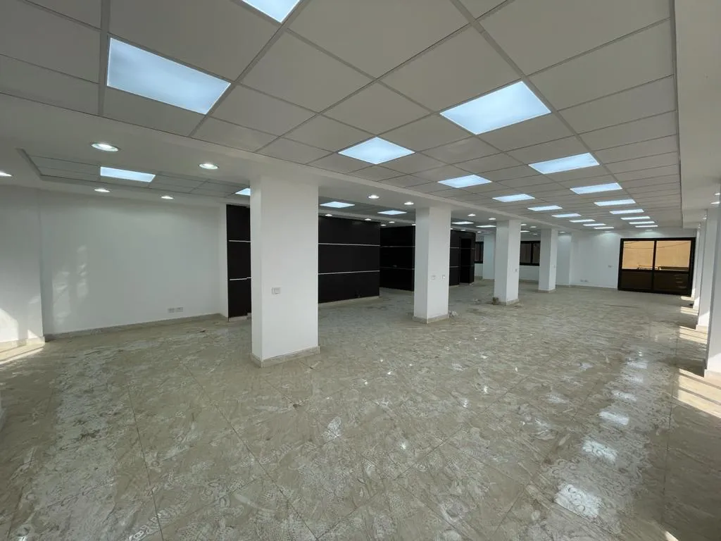 Bright open sales floor with ceiling panel lights and square columns in a shop for rent in Sarayat, Maadi