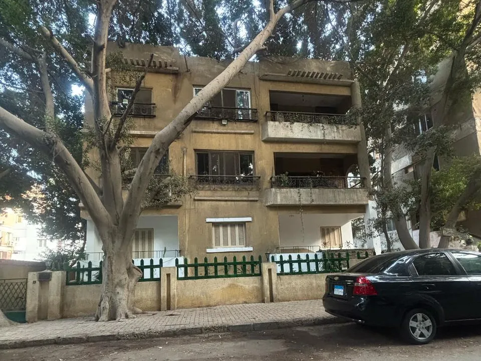 Three-storey townhouse facade behind a green fence on a tree-lined street in Sarayat, Maadi, Cairo