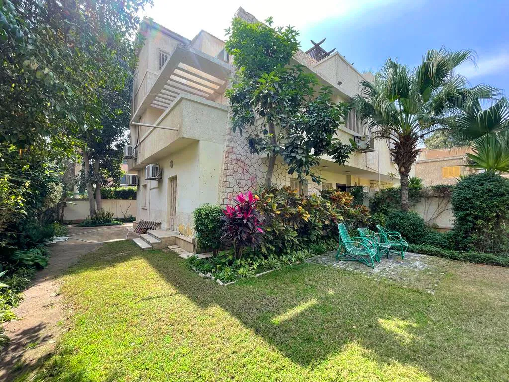 Private lawn with palms and flowering shrubs in front of a villa in Degla, Maadi