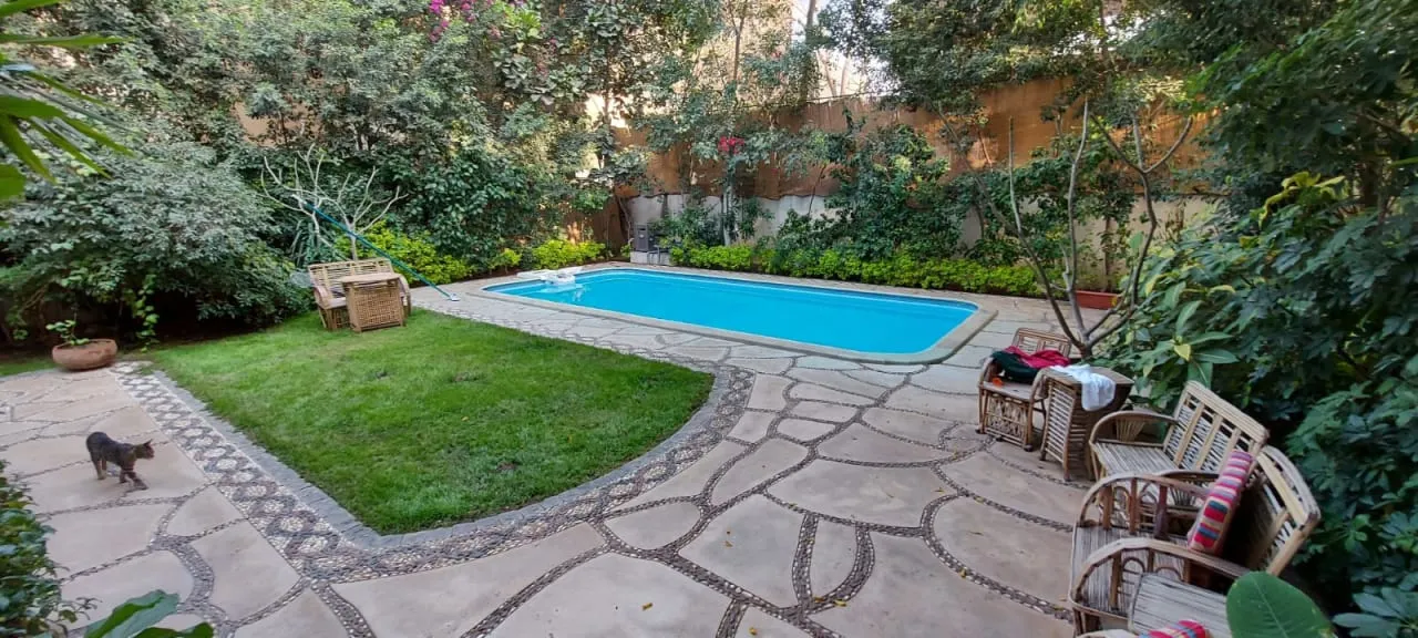 Private swimming pool with a lawn and stone paving in the garden of a villa in Degla, Maadi