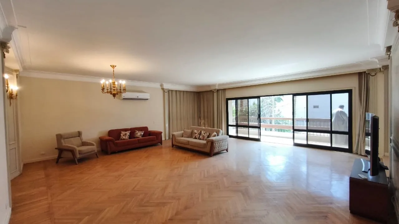 Long parquet-floored living room with classic sofas and a glazed balcony wall, in an apartment for rent in Degla