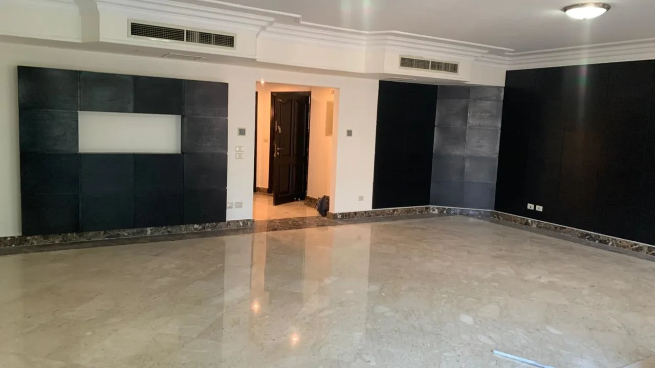 Wide empty reception with polished marble flooring and dark stone feature walls, in an apartment for sale in Degla