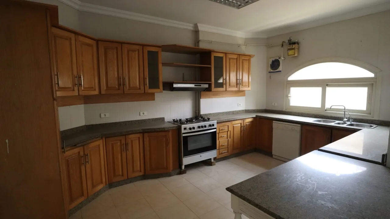 Kitchen with wooden units, a freestanding cooker and an arched window, in a semi-furnished apartment for rent in Degla