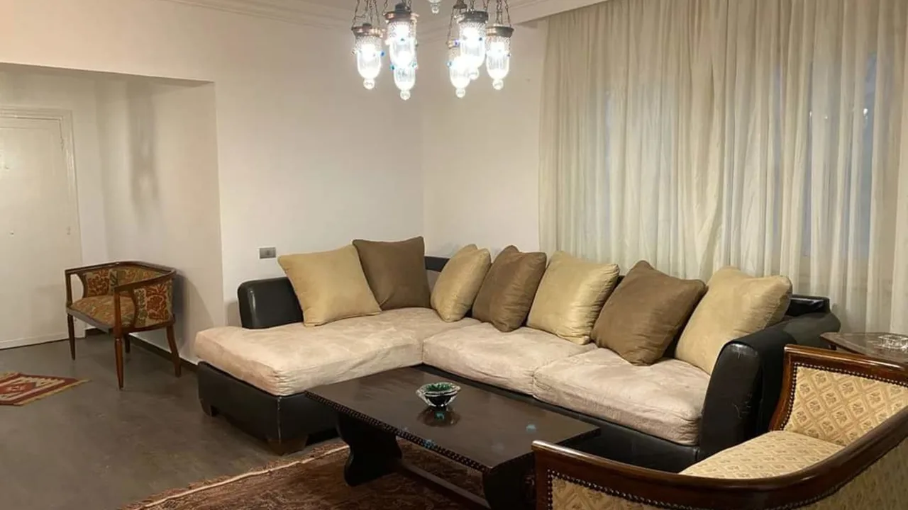 Furnished living room with a corner sofa and full-height curtains, in a ground floor apartment for sale in Degla
