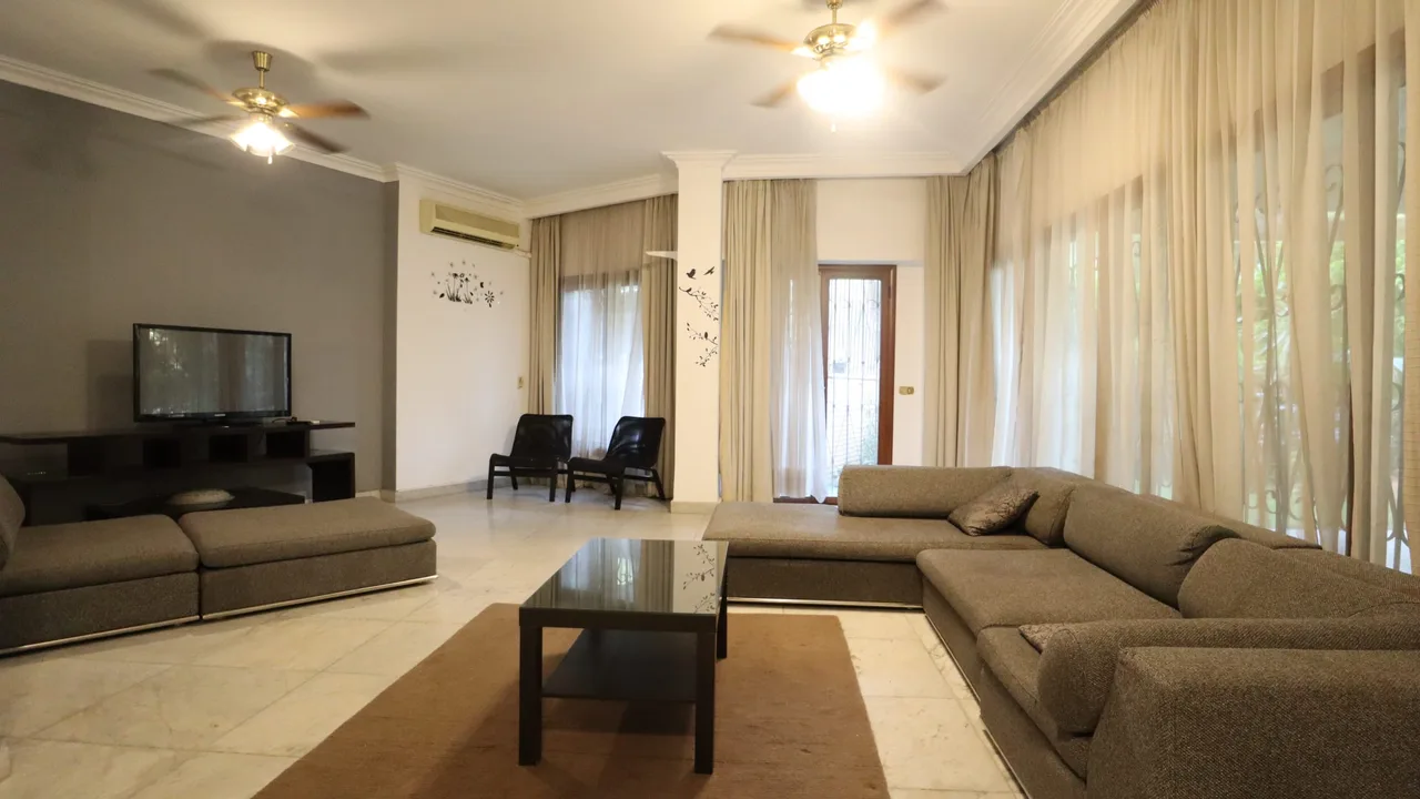 Living room with two corner sofas and curtained doors onto the garden, in a ground floor apartment for rent in Degla
