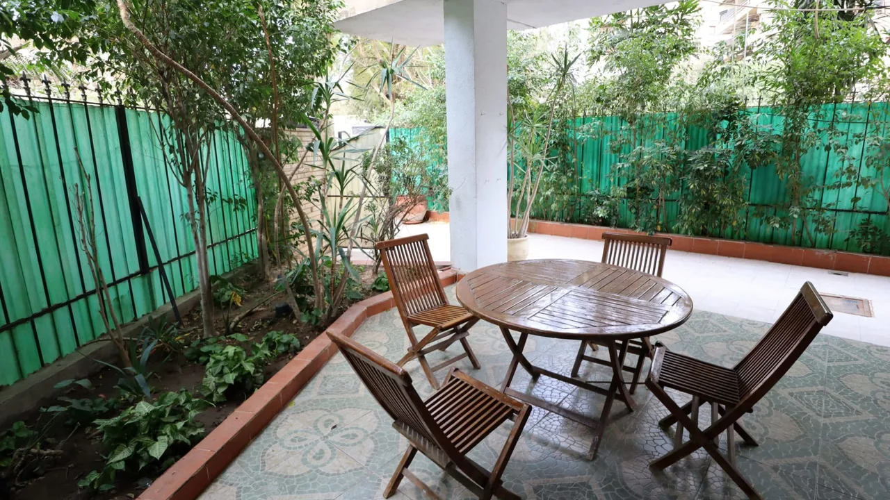 Garden terrace with a wooden table under the trees, at a ground floor apartment for rent in Degla