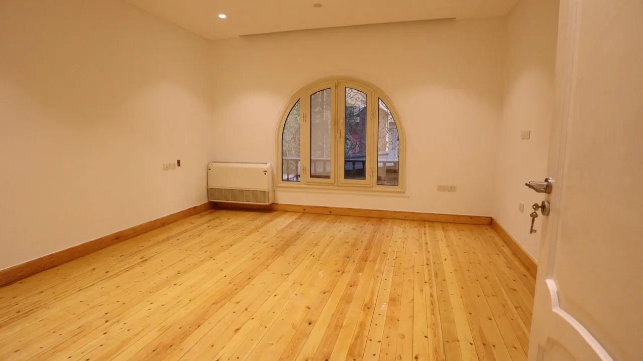 Bare room with pine flooring, plain walls and an arched window, waiting to be fitted out, in an office for rent in Degla