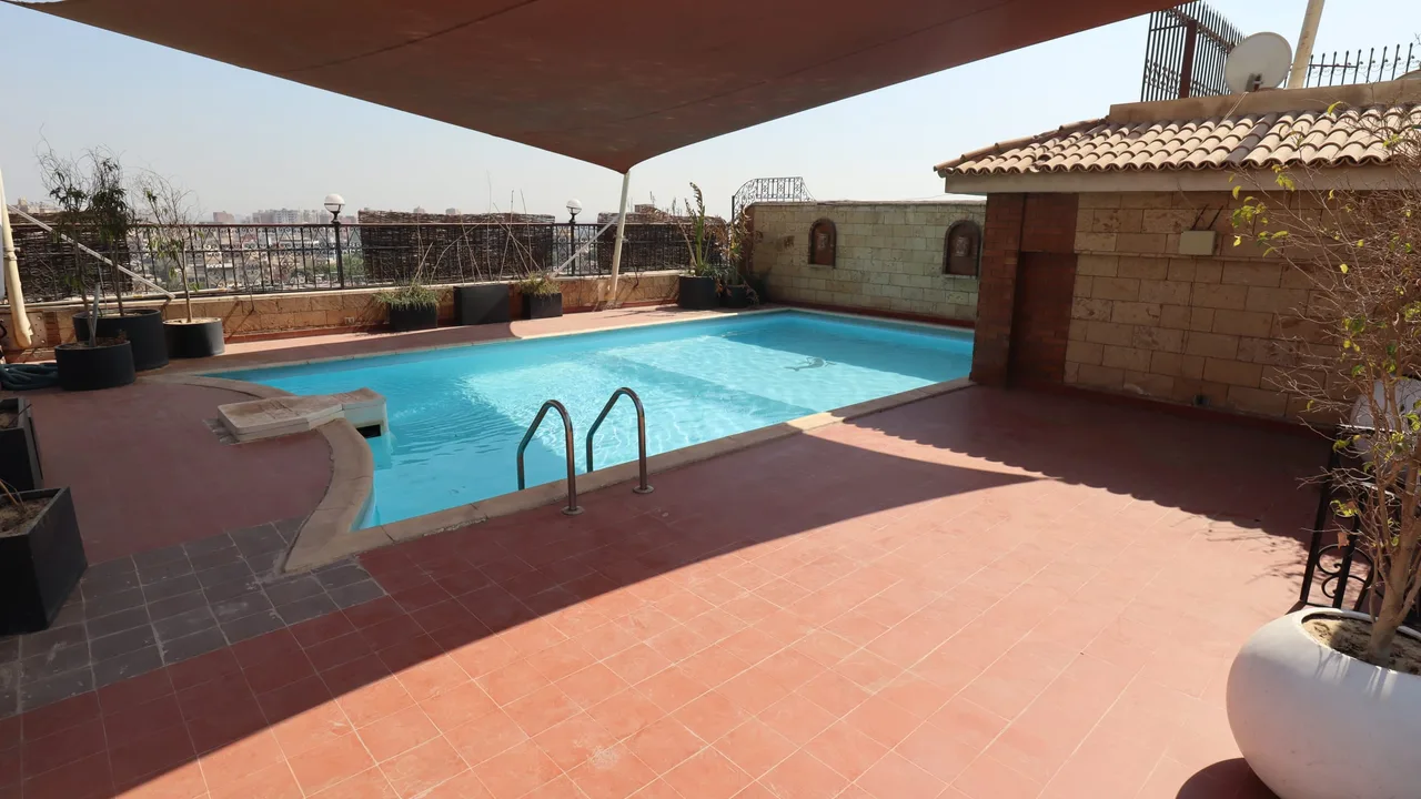 Rooftop swimming pool with a shade sail, tiled deck and planters, at a penthouse for rent in Degla