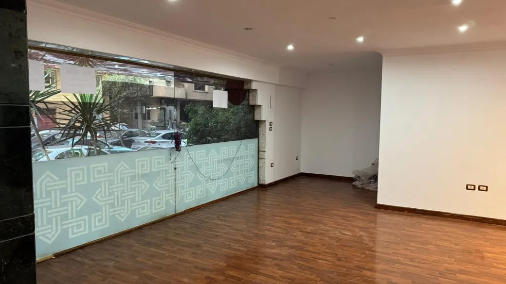 Glazed street frontage of a retail shop in Degla, looking out onto trees and parked cars