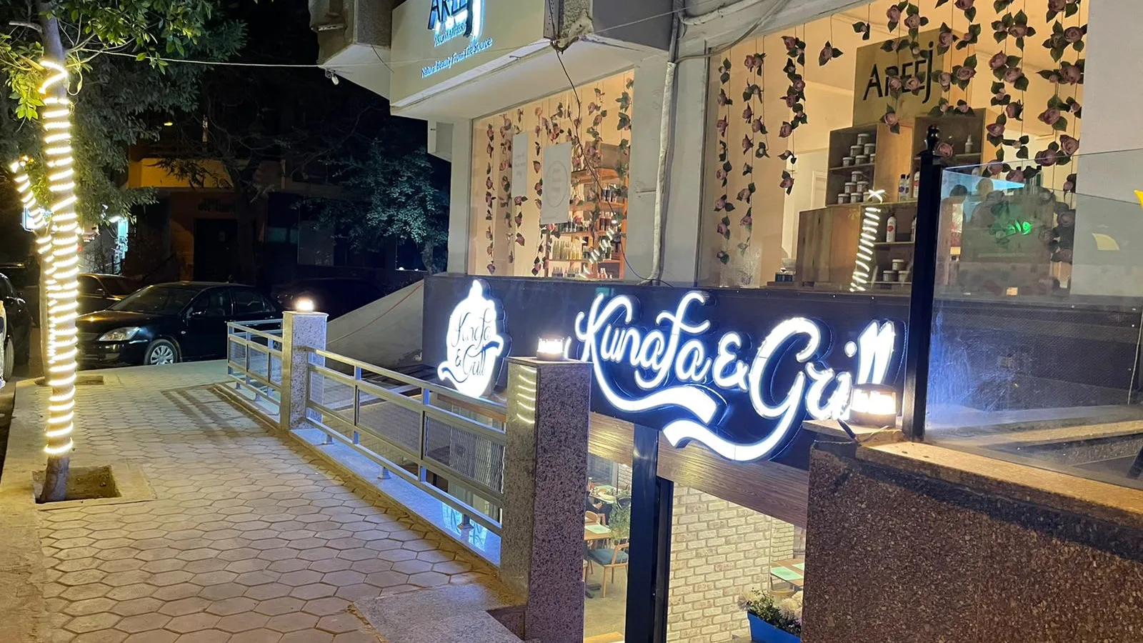 Lit shopfront and signage of a fitted food business on a Degla street at night