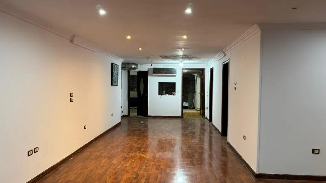 Empty commercial floor with polished wood flooring and recessed ceiling lights, in a shop for rent in Degla
