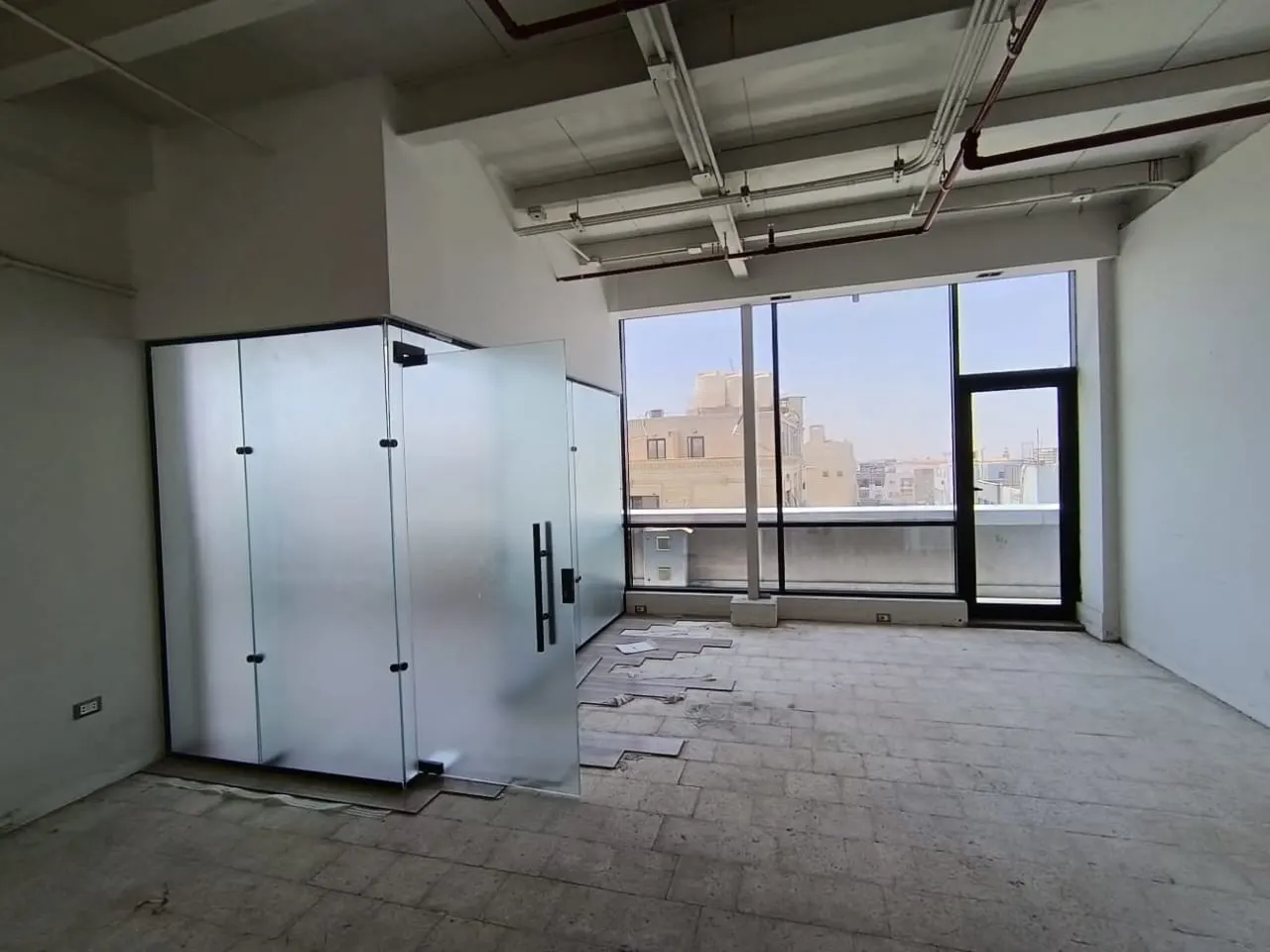 Glass-partitioned rooms and a balcony door in a 110 m² administrative office for rent in First Settlement