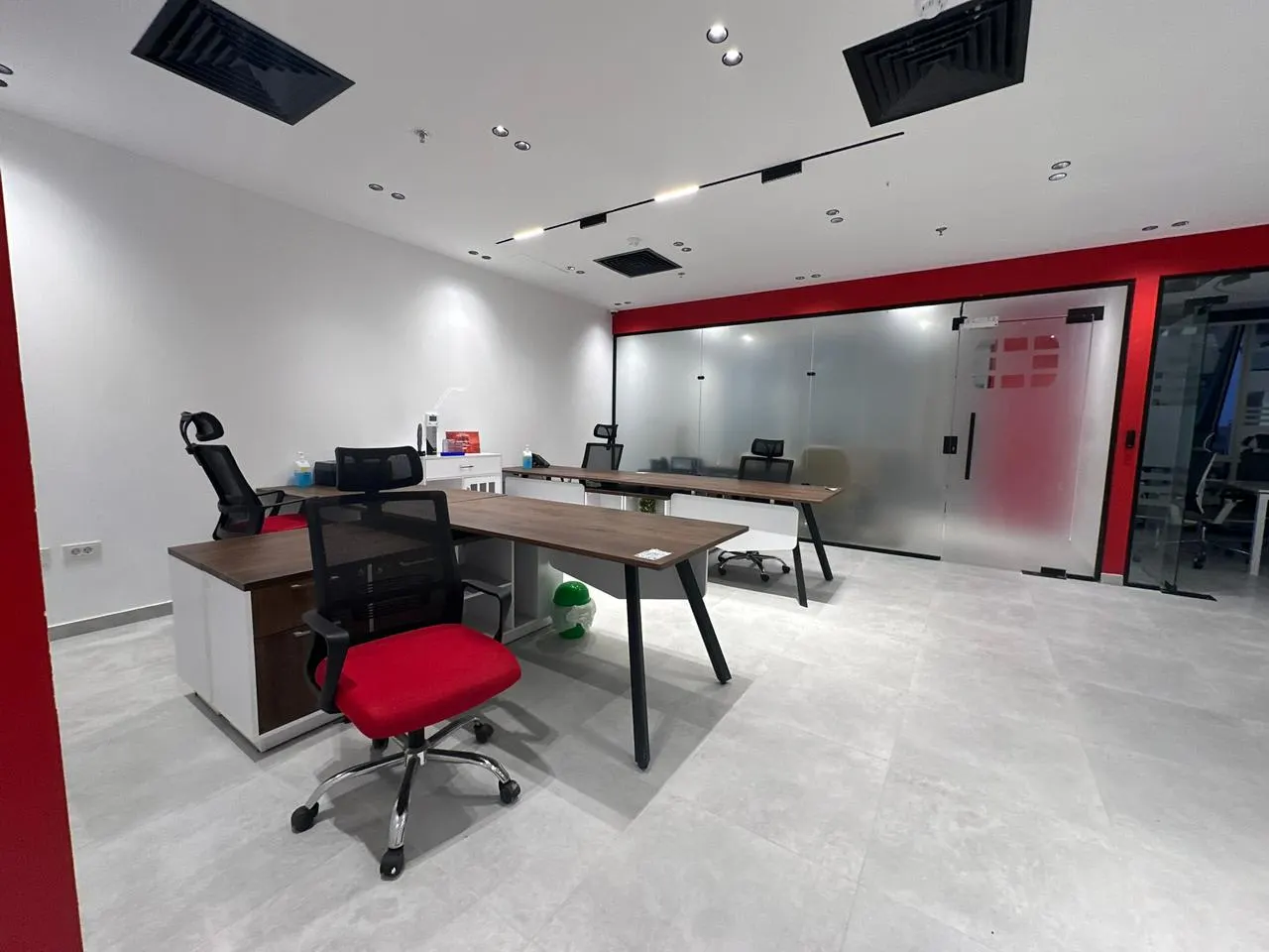 Furnished manager's office with a desk and red accent wall in a 720 m² office for rent in First Settlement