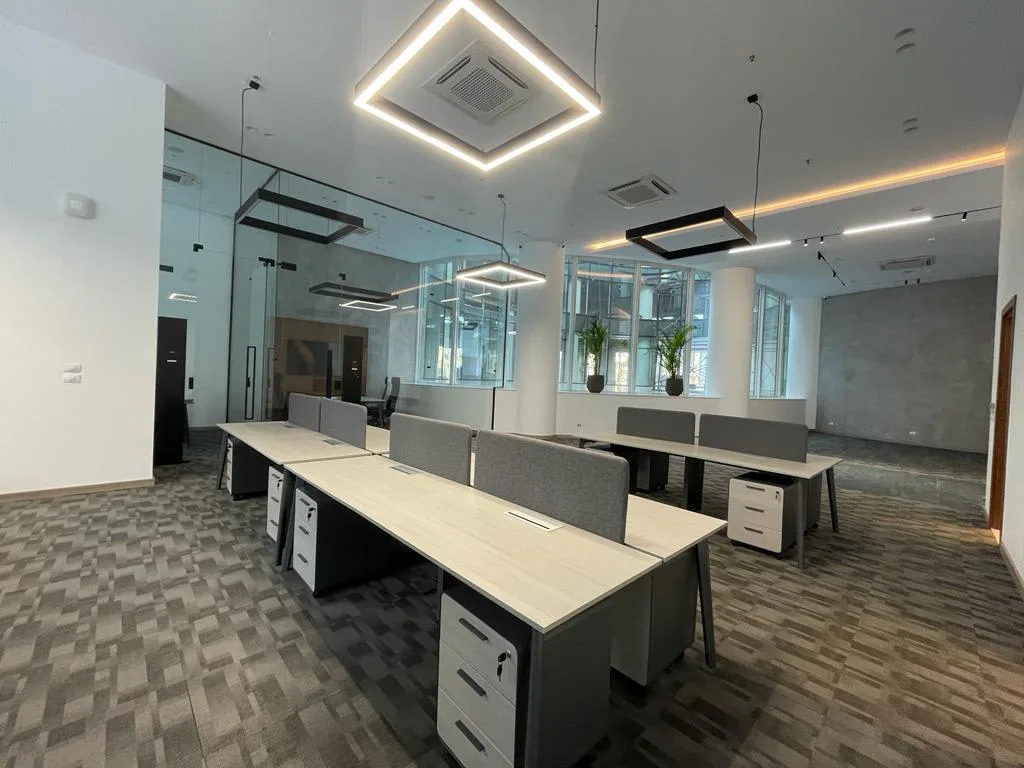 Fitted open-plan office with workstations, glass partitions and square light fittings in a building in New Cairo
