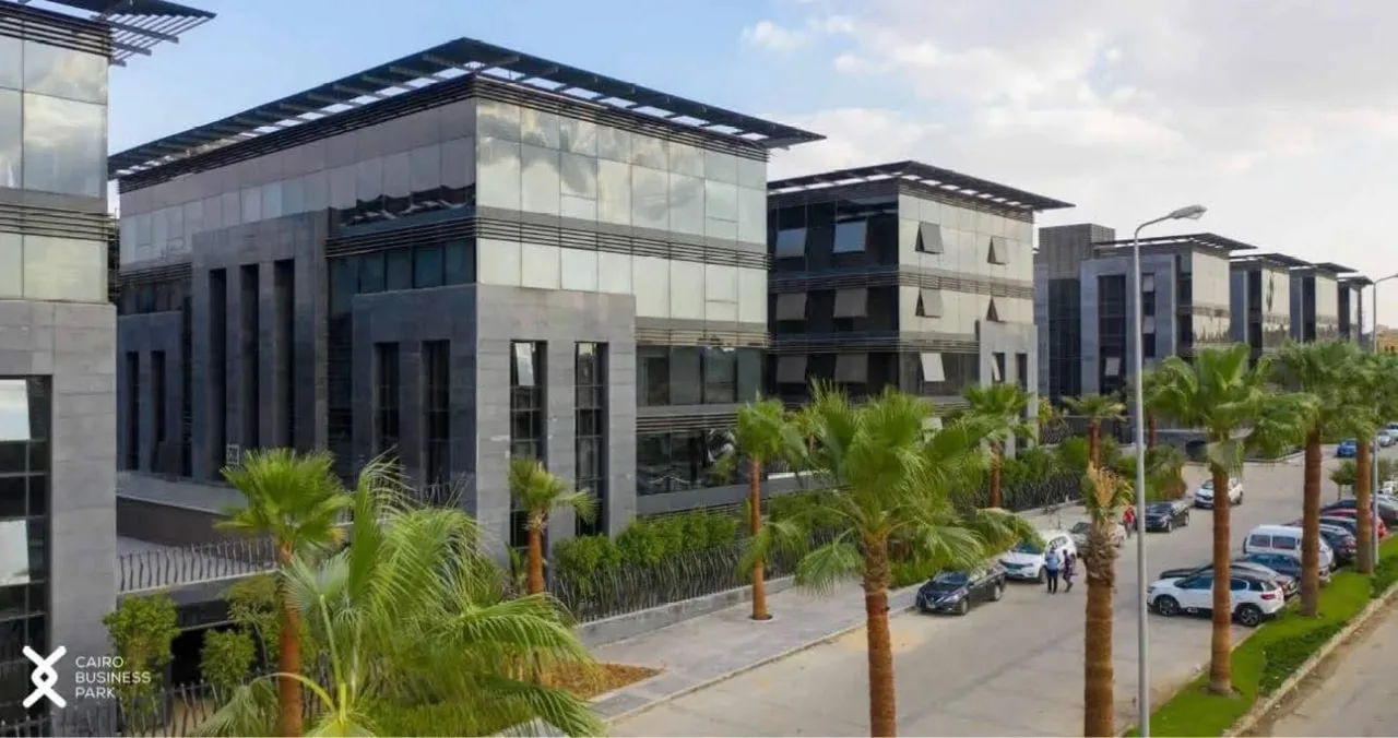Glass and stone office buildings along a palm-lined street in a business park on South 90th Street, New Cairo