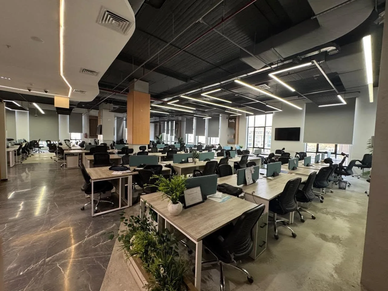 Open-plan office floor with rows of workstations and planters in an office for rent in Fifth Settlement, New Cairo