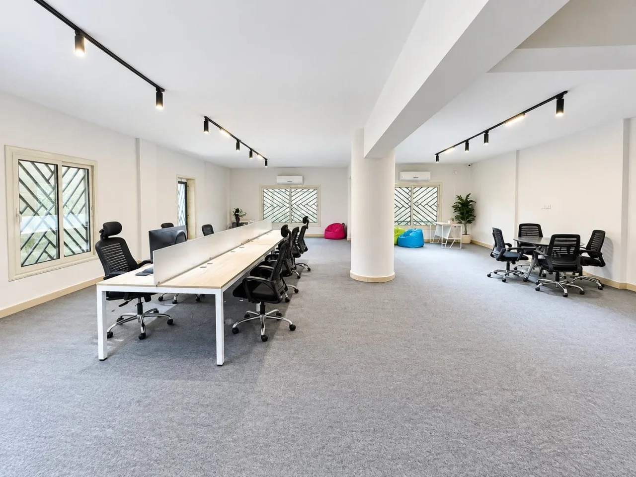 Fully finished office with grey carpet, track lighting and a long workstation bench in New Cairo