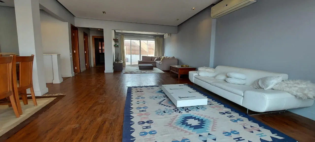 Long living room with a white sofa, kilim rug and wood floors in a 500 m² penthouse in New Cairo