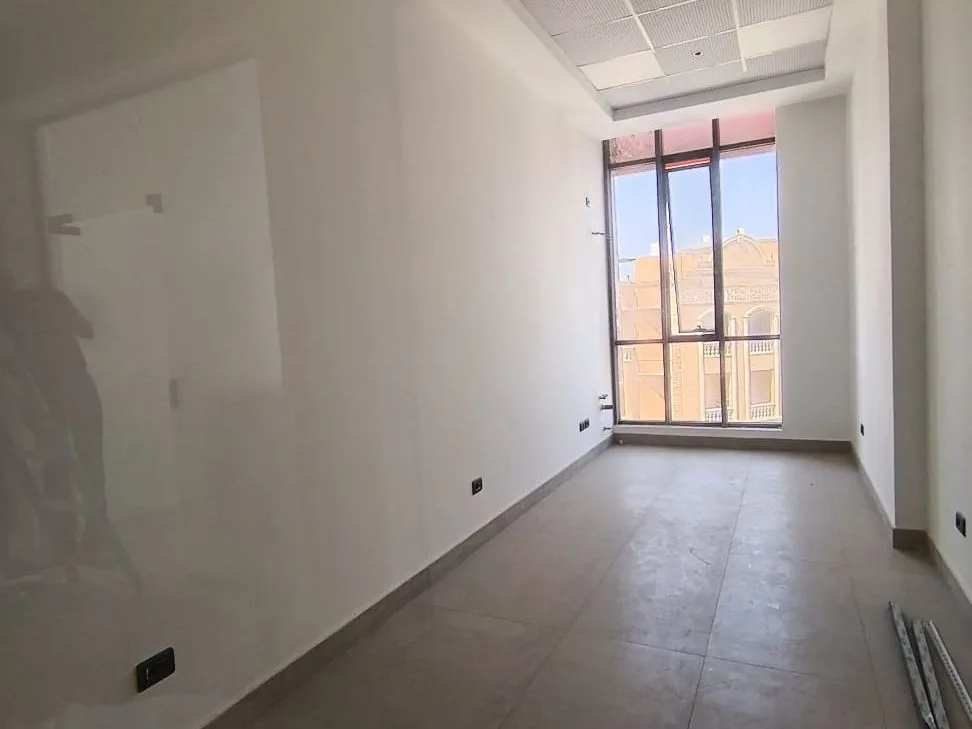 Finished 30 m² shop for rent in New Cairo with tiled floor, white walls and a tall window at the far end