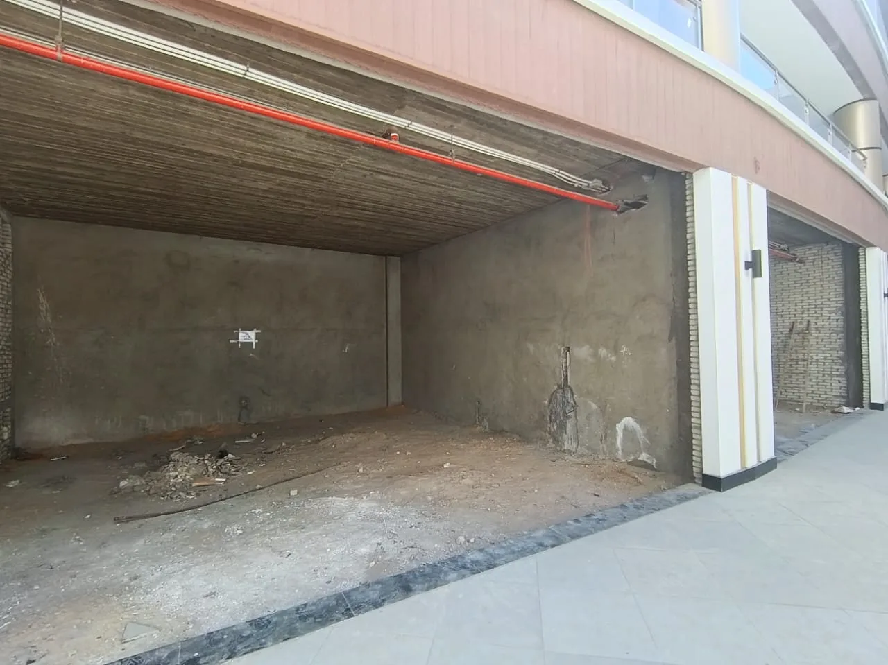 Open-front shop unit with bare concrete walls and ceiling awaiting fit-out in a New Cairo mall