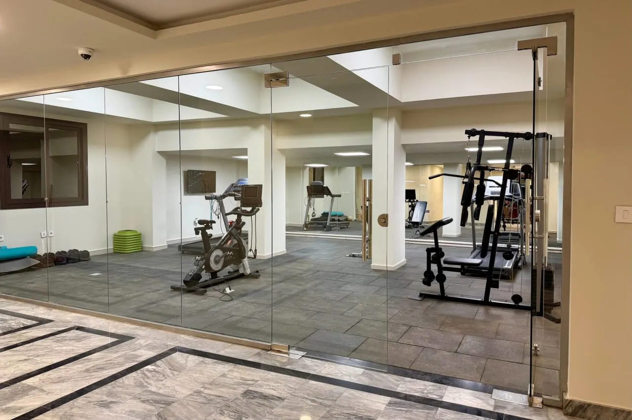 Glass-walled gym with an exercise bike and weight machine in a serviced apartment building in New Cairo