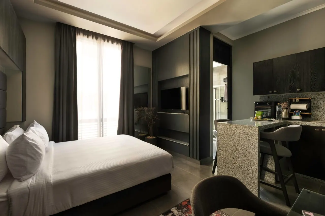 Bed, kitchenette and TV in one room of a modern serviced studio with roof access in New Cairo