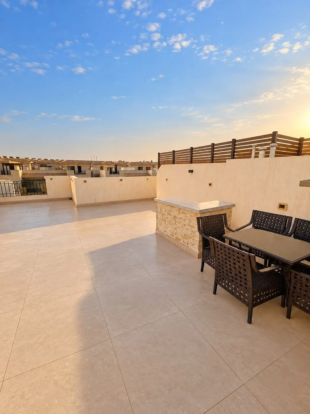 Tiled roof terrace with a dining table and chairs at sunset above a studio for rent in New Cairo