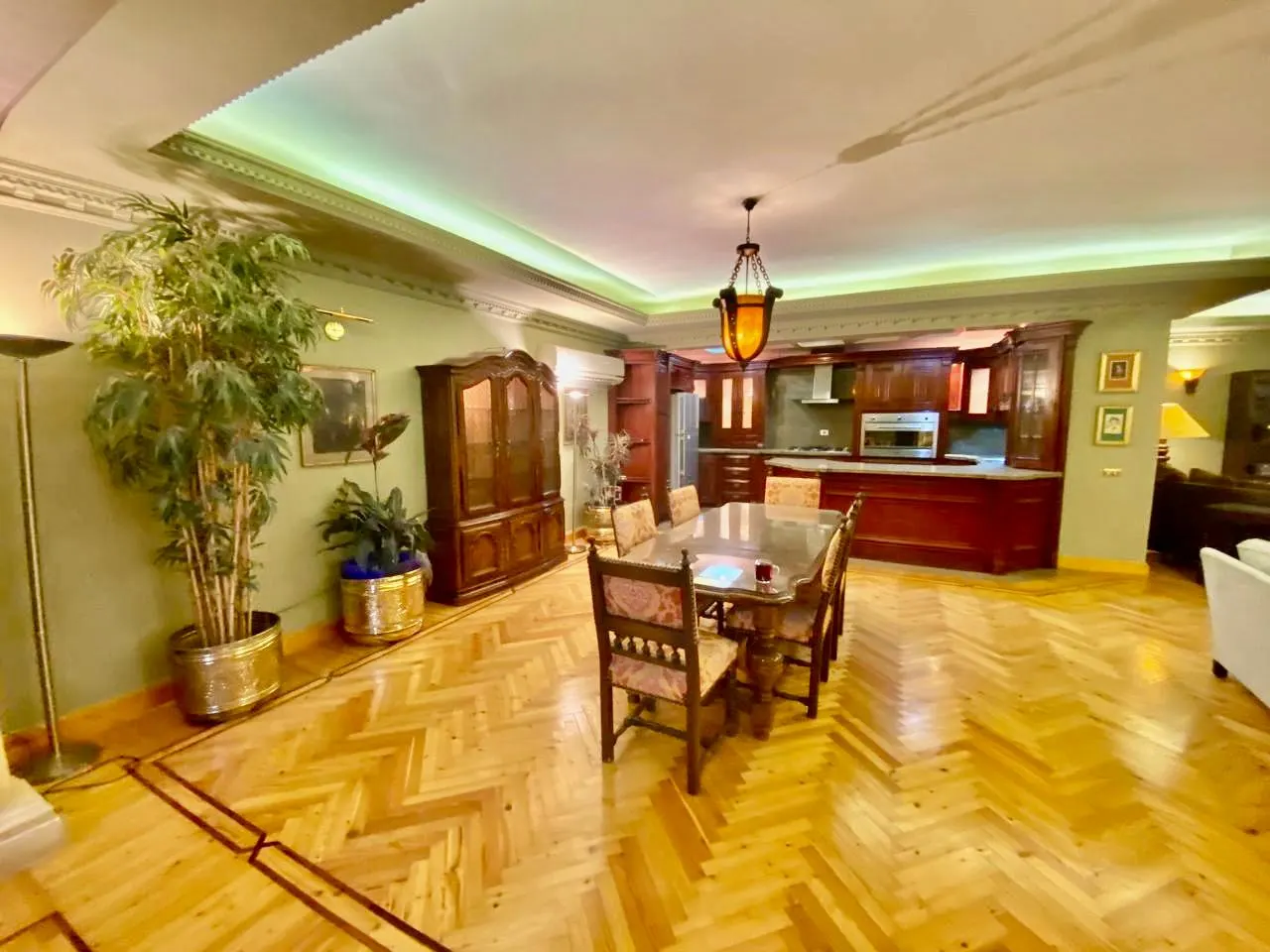 Furnished open living and dining area with parquet floors and a wood kitchen in a villa in Fifth Settlement, New Cairo