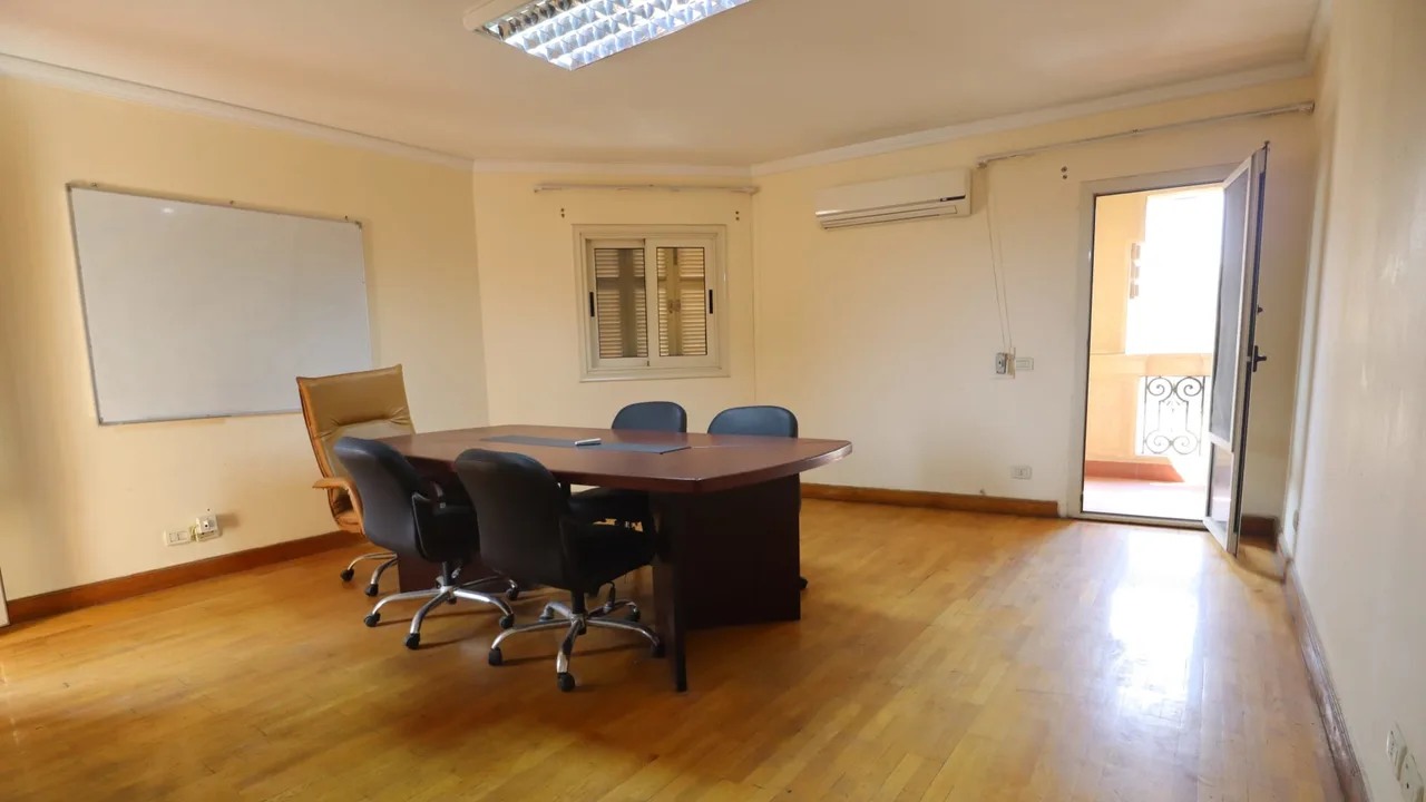 Furnished meeting room with a boardroom table, office chairs and a whiteboard in a furnished office for rent in Sarayat El Maadi
