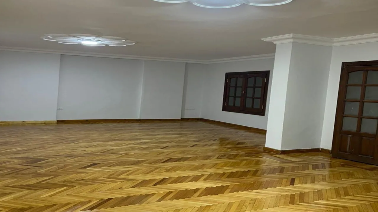Empty parquet-floored reception area with wooden doors in a 200 m² administrative office for rent in Sarayat El Maadi