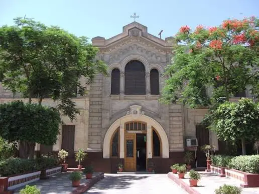 واجهة حجرية مقوسة ومدخل مبنى مدرسة تاريخية في الزمالك تحيط به الأشجار