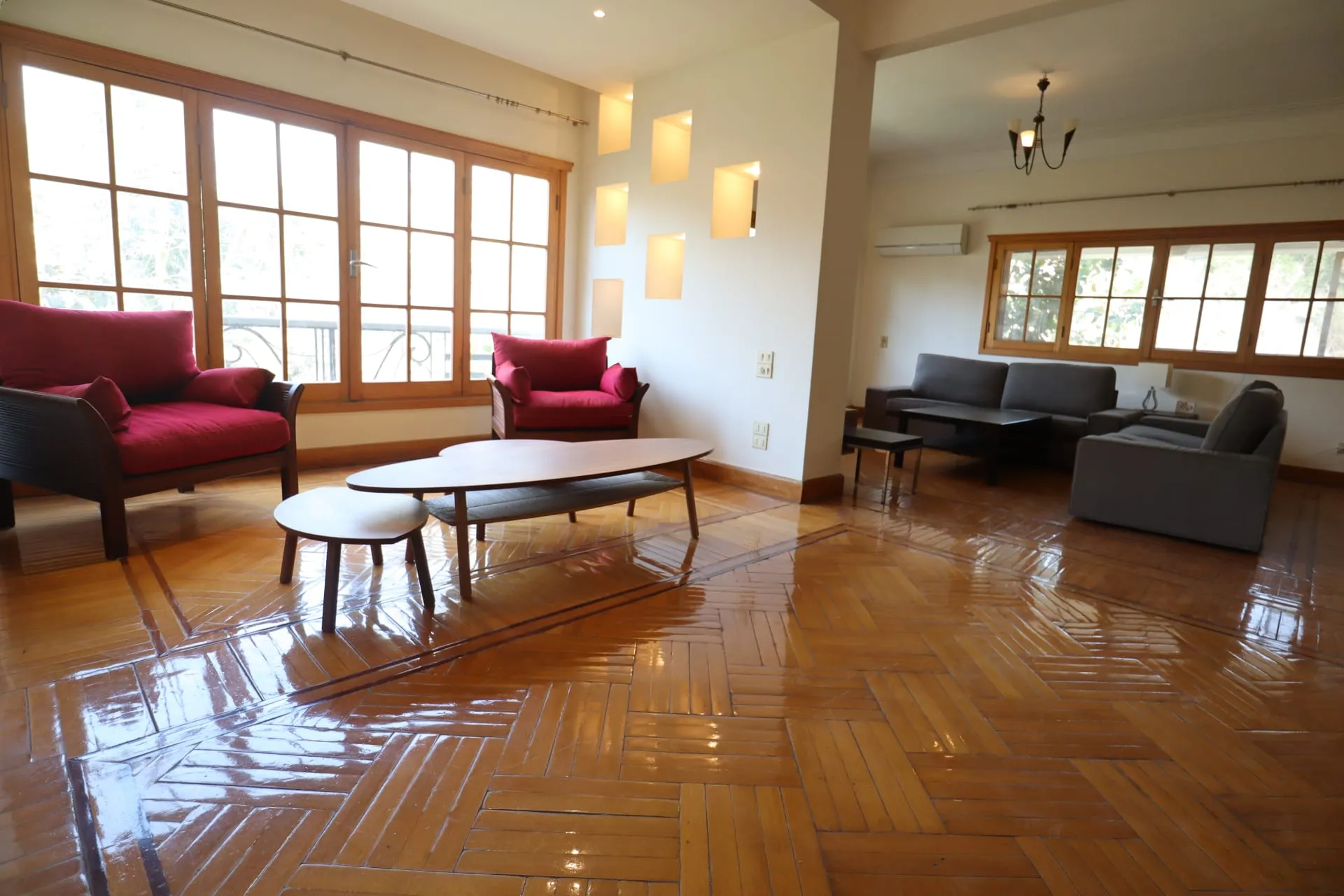 Furnished duplex living room in Sarayat, Maadi, Cairo with red armchairs, parquet floor and tall wooden windows
