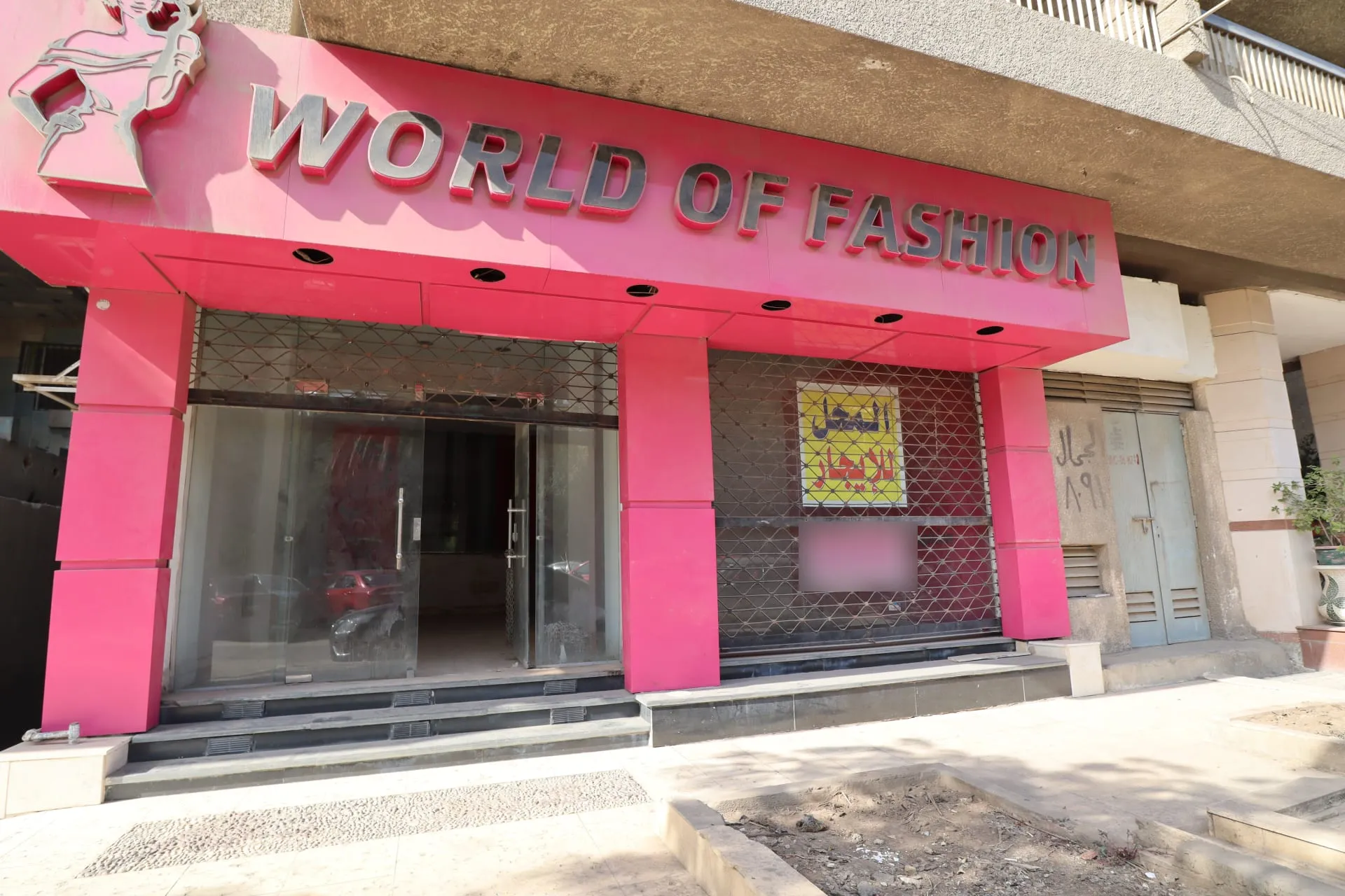 Pink shopfront with a large sign and glass doors behind a rolling shutter, a shop for rent in Maadi, Cairo