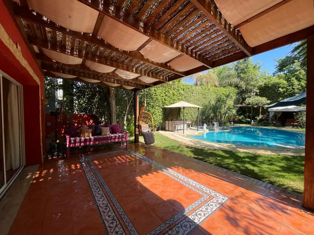 Shaded pergola terrace beside a private swimming pool and garden at a villa in the Fifth Settlement, Cairo